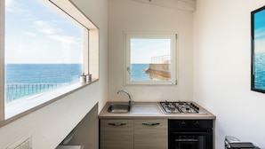 Een compacte keuken met uitzicht op zee, een gasfornuis en een spoelbak.