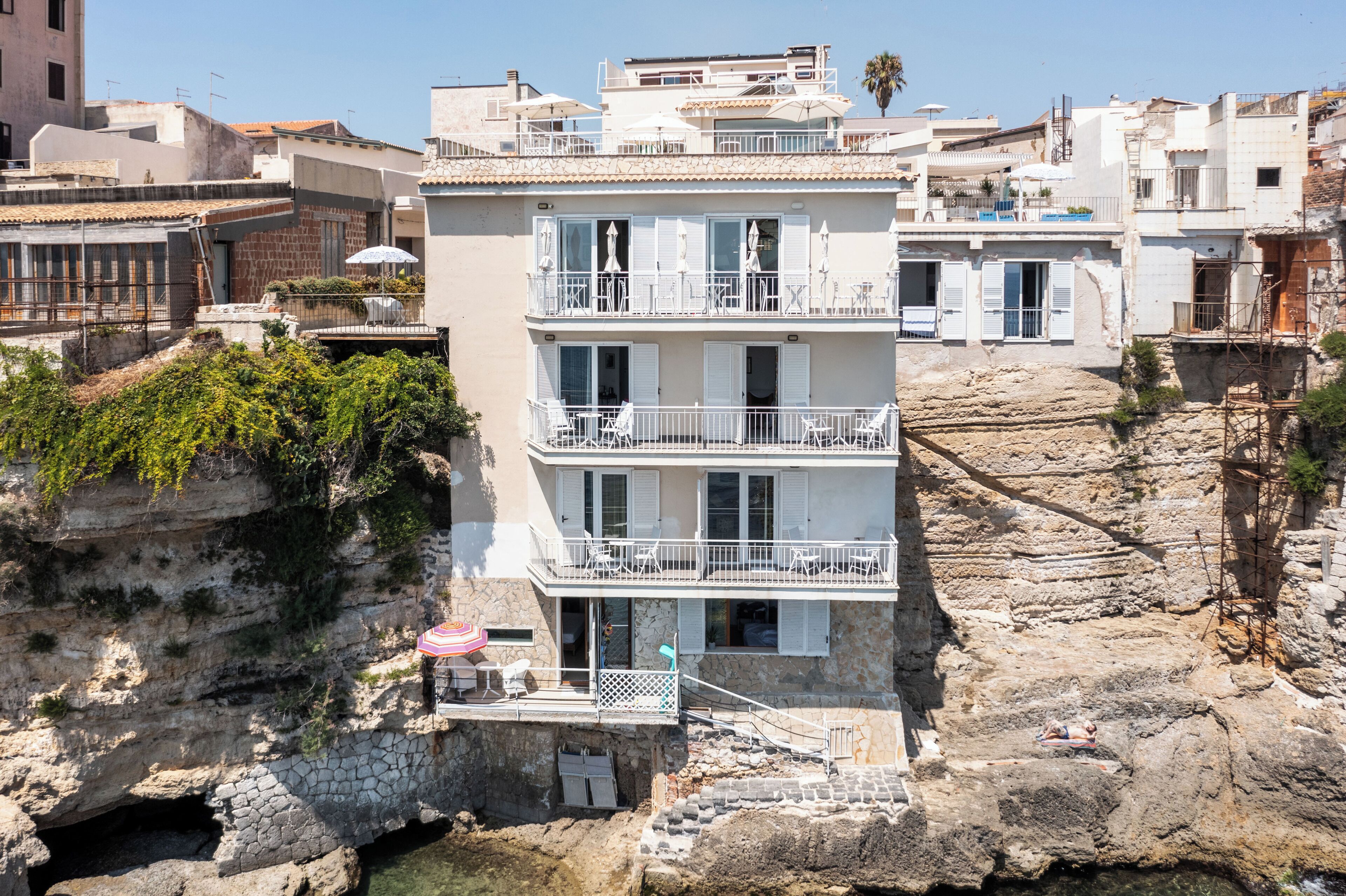A multi-story building with balconies, a pool area, and a view of rocky terrain.