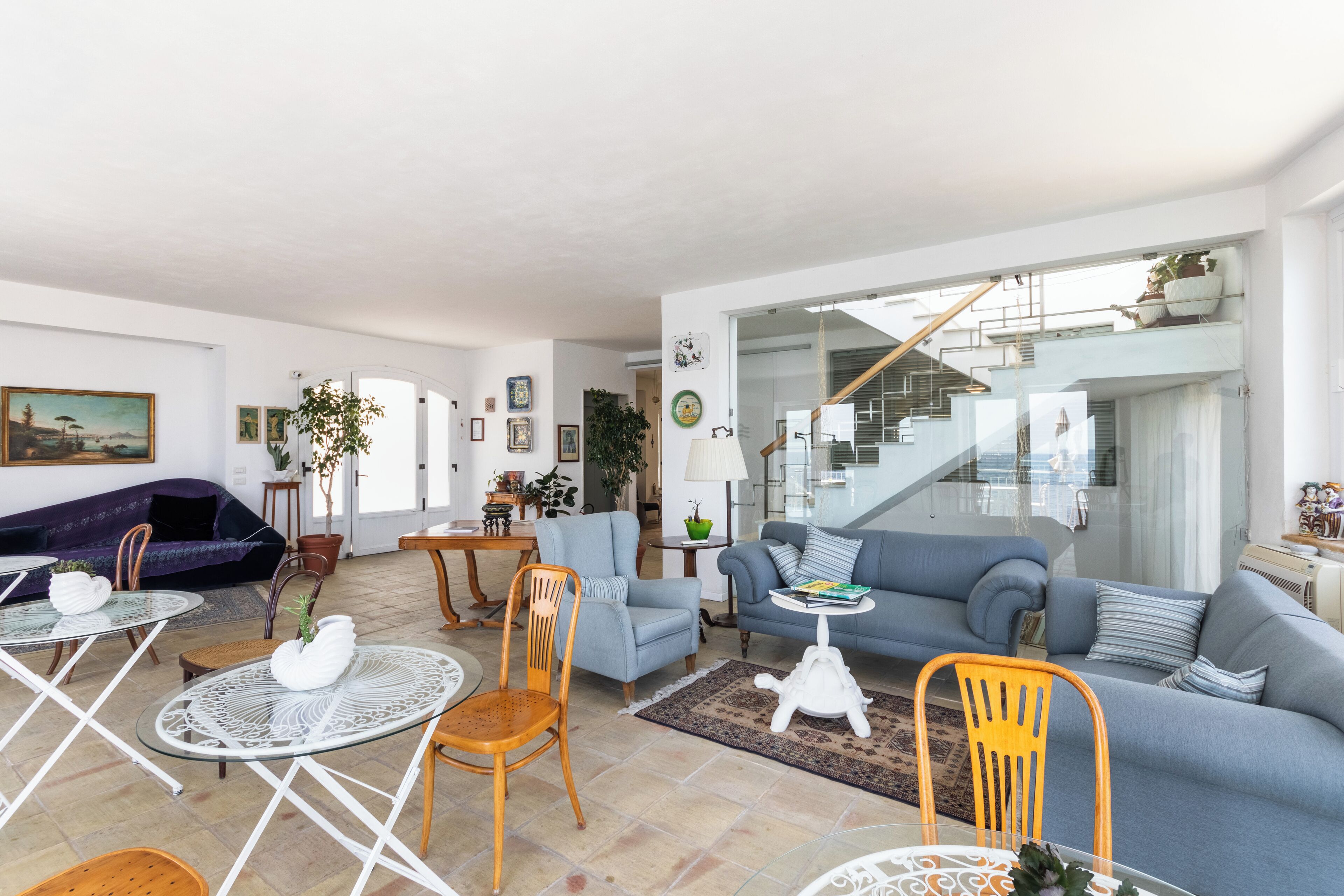 A spacious living room with a sofa, chairs, a coffee table, and a staircase leading to an upper level.