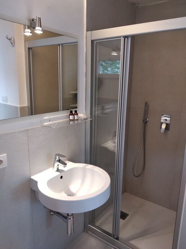 A modern bathroom with a white sink, a glass shower enclosure, and a mirror above the sink. - Giuggiulena Villa (Syracuse)