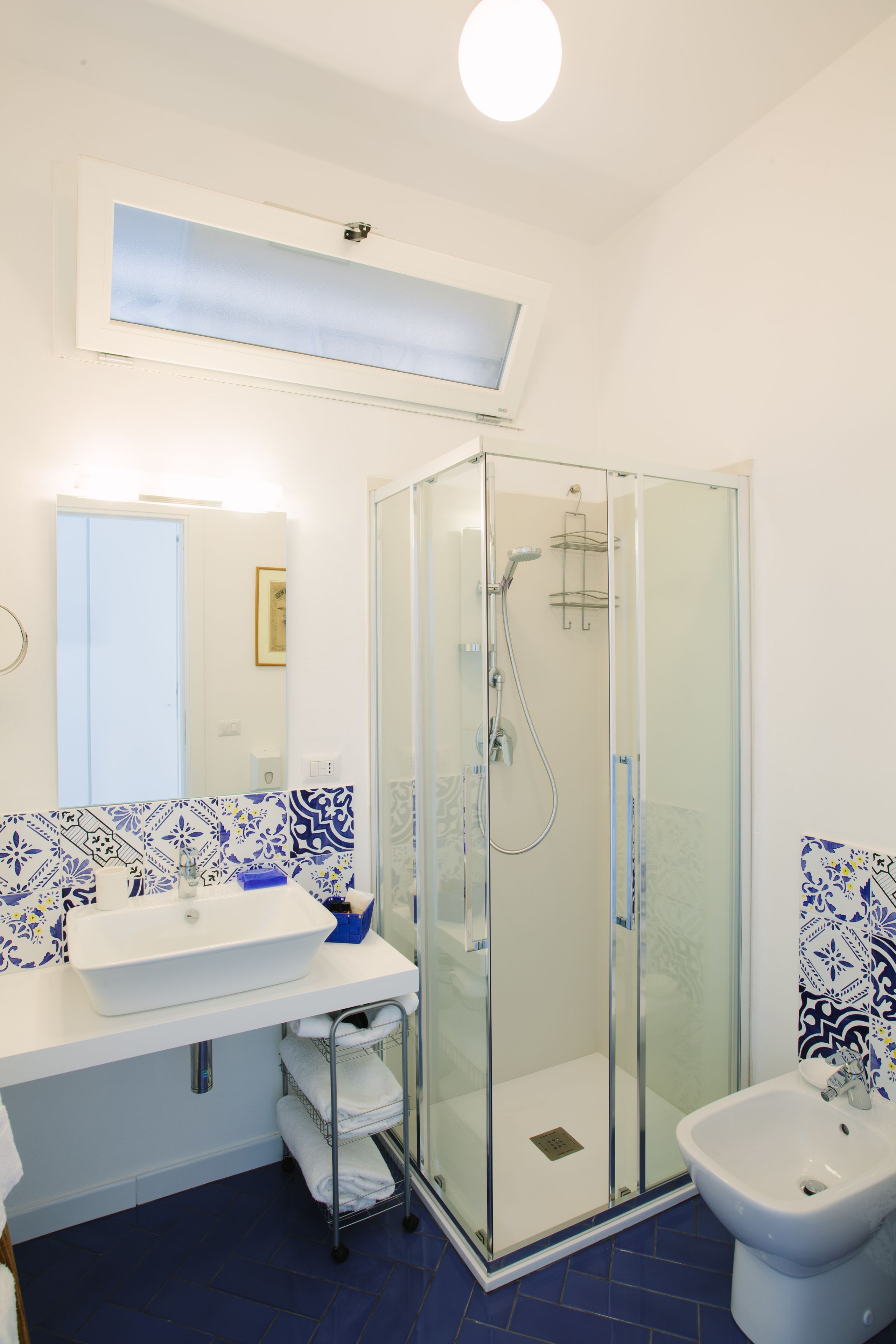 Een badkamer met een douchecabine van glas, een witte wastafel en een bidet.