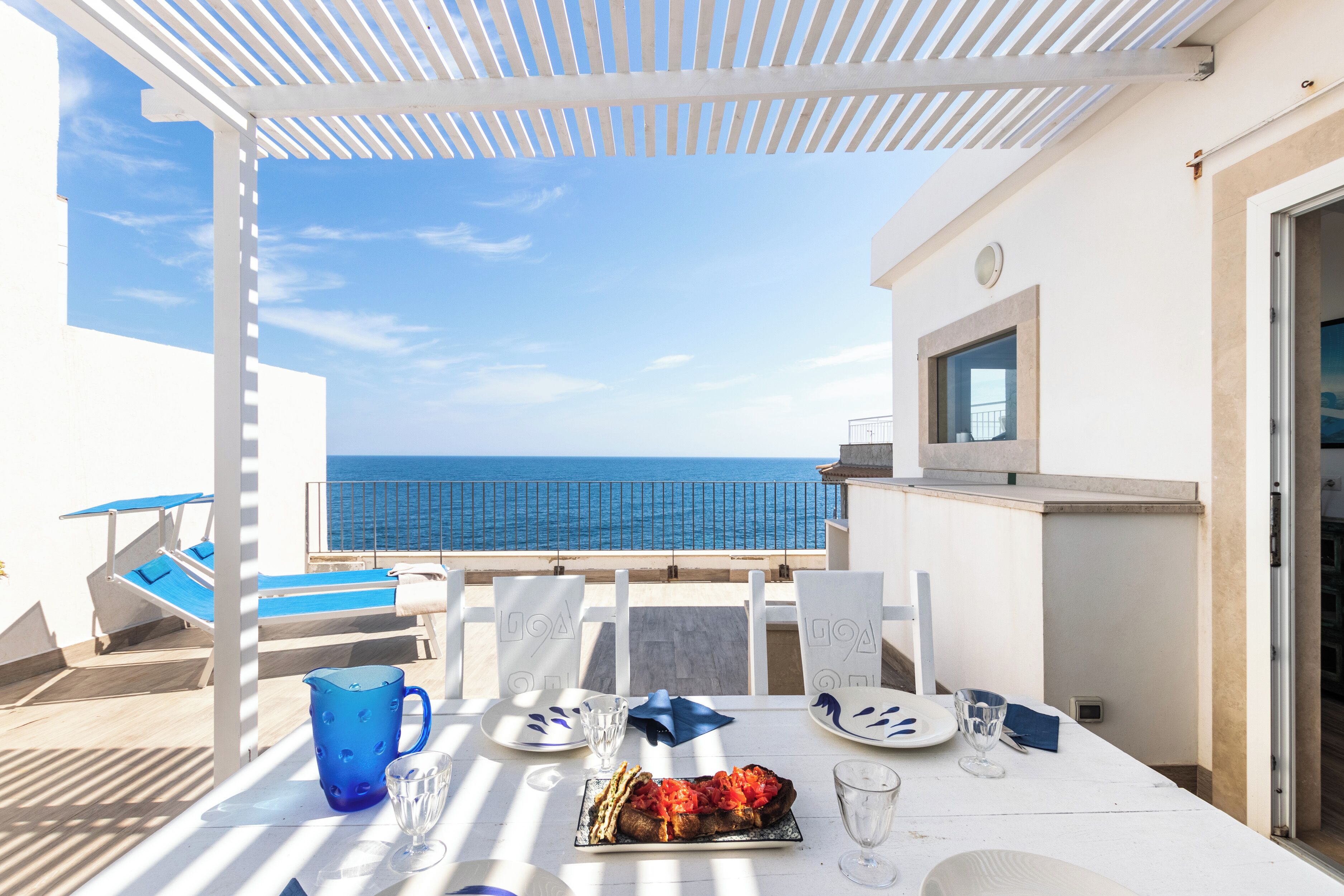 Une terrasse avec une table dressée pour le dîner, offrant une vue sur la mer.