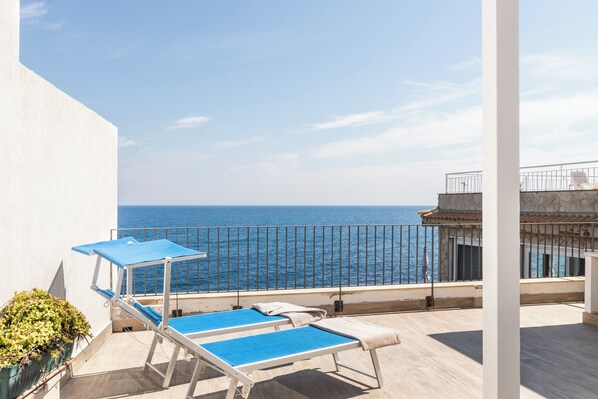 A balcony with two sun loungers and a potted plant.