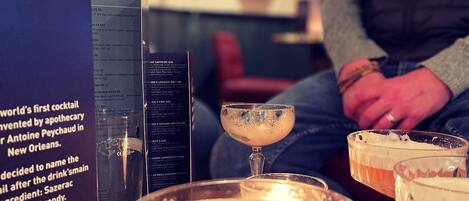 A bar area with a menu board, a cocktail glass with a fruit garnish, and a person in the background.