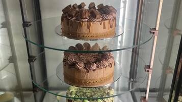 Un expositor escalonado con varios pasteles y pequeños vasos de postres.