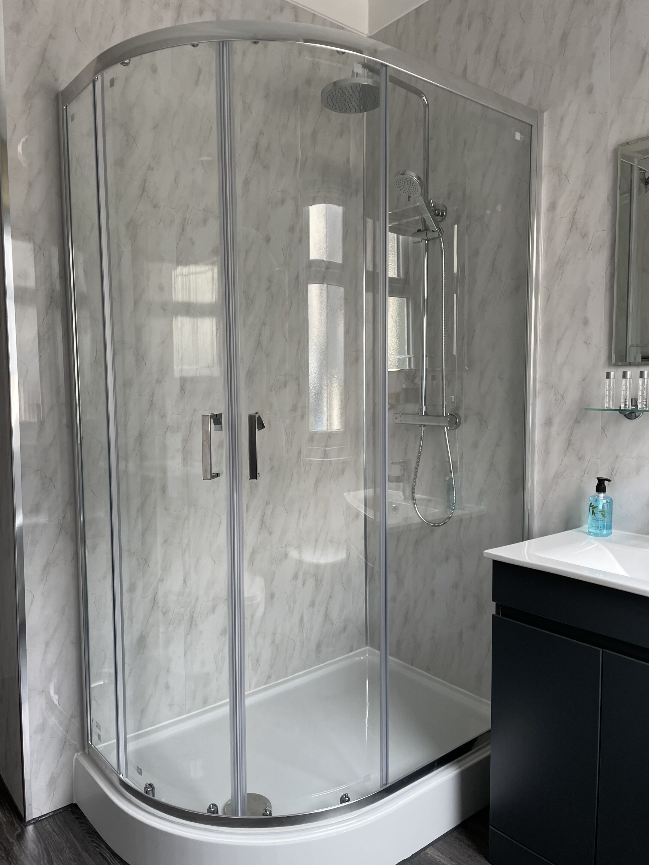 A modern bathroom with a glass-enclosed shower, a white sink, and a dark-toned cabinet.