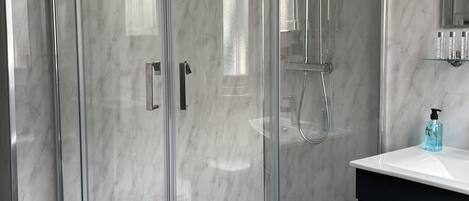 A modern bathroom with a glass-enclosed shower, a white sink, and a dark-toned cabinet.