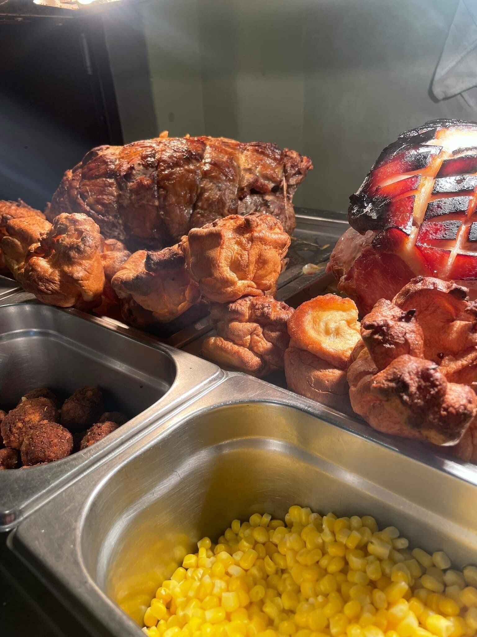 A buffet with roasted meats, corn, and other dishes.