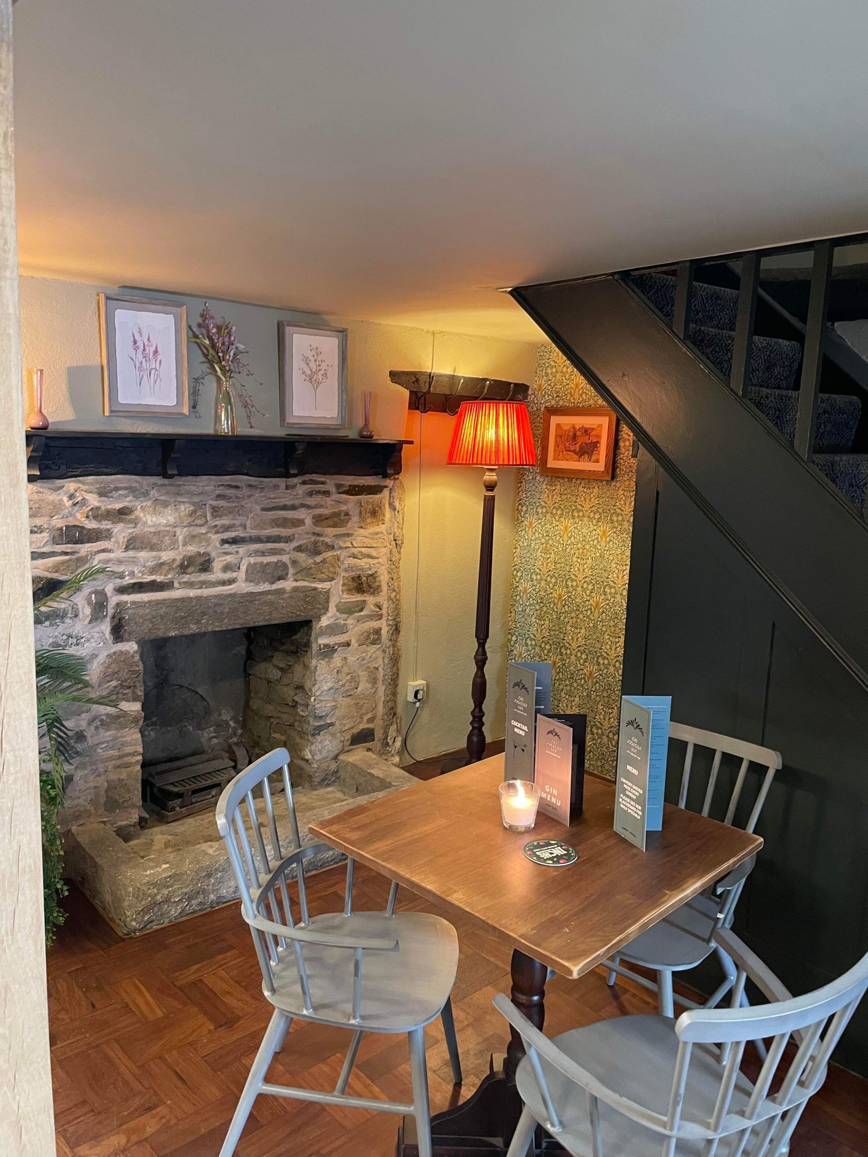 A cozy dining area with a stone fireplace, wooden table, and white chairs.