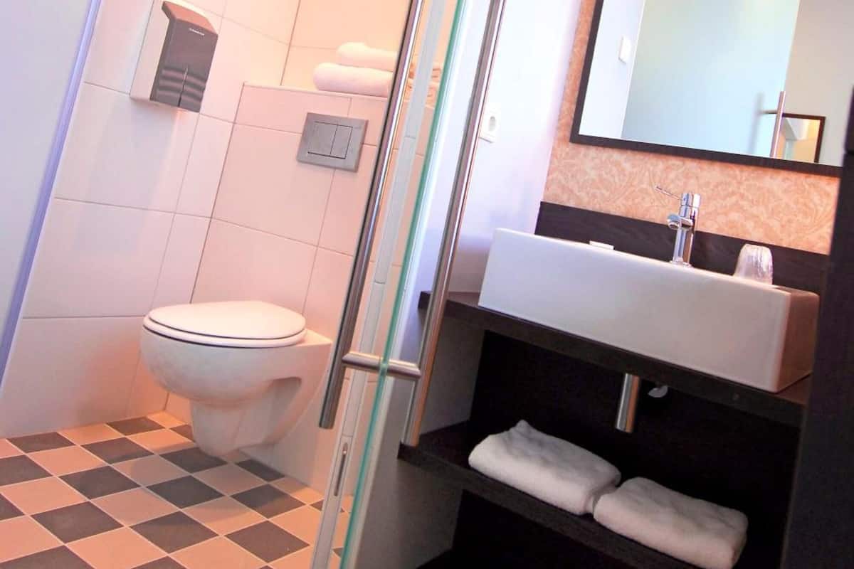 Une salle de bain comprenant des toilettes, un lavabo, un miroir et un espace douche.