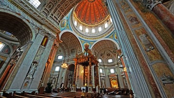 An interior of a grand cathedral with high vaulted ceilings, ornate columns, and a central altar.