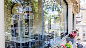 Un restaurant doté d’une terrasse, de murs en verre et d’une façade en briques.