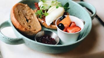 A breakfast plate with toast, eggs, and berries, a cup of coffee, and a glass of orange juice on a table.