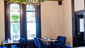 Un coin repas avec des chaises bleues, un lustre et une fenêtre avec des rideaux.