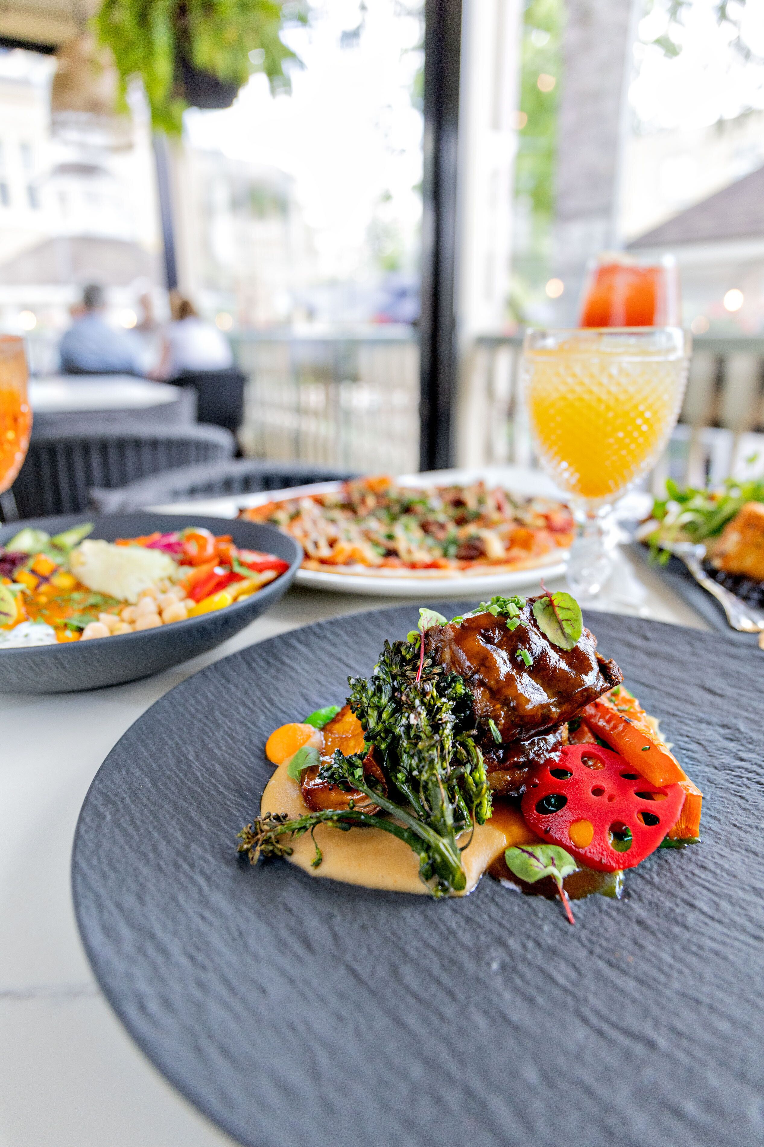 A restaurant setting with a table set for dining, featuring plates of food and a glass of orange juice.
