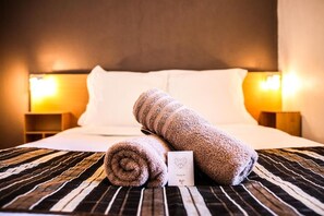 A neatly made bed with rolled towels and a card on the bed. - Villa Florida (Bandol)
