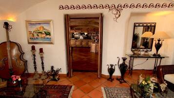 Um quarto com porta de madeira que dá para uma cozinha, um candelabro, um quadro emoldurado e um espelho com uma luminária.