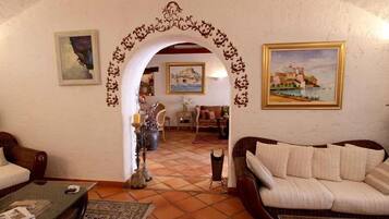 A living room with a tiled floor, two sofas, a coffee table, and a decorative archway.