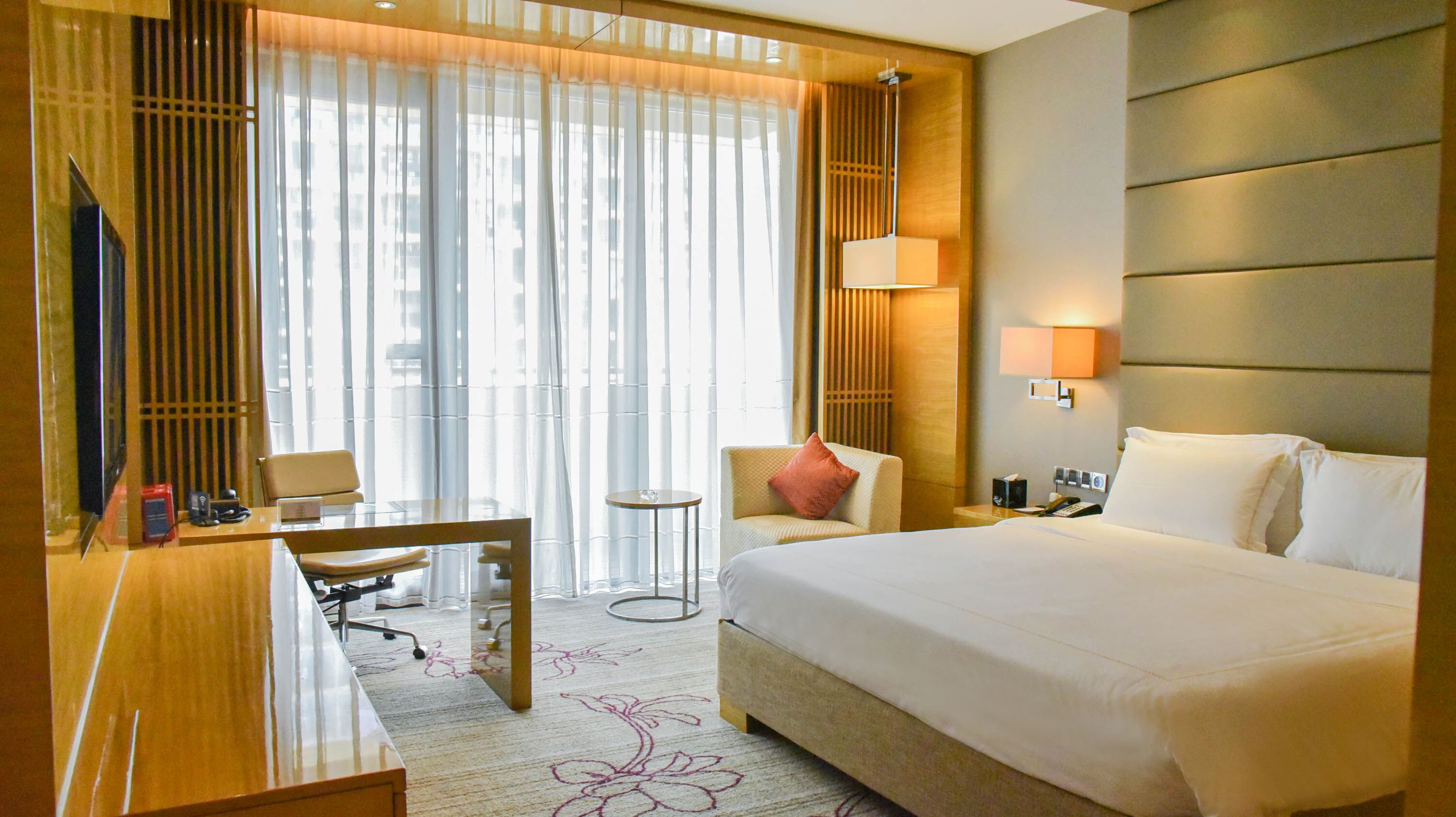 Une chambre d’hôtel avec un grand lit, un bureau avec une chaise, une petite table et un téléviseur.
