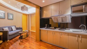 Una cocina compacta con electrodomésticos modernos, una zona de comedor con sofá y mesa de centro, y piso de madera.
