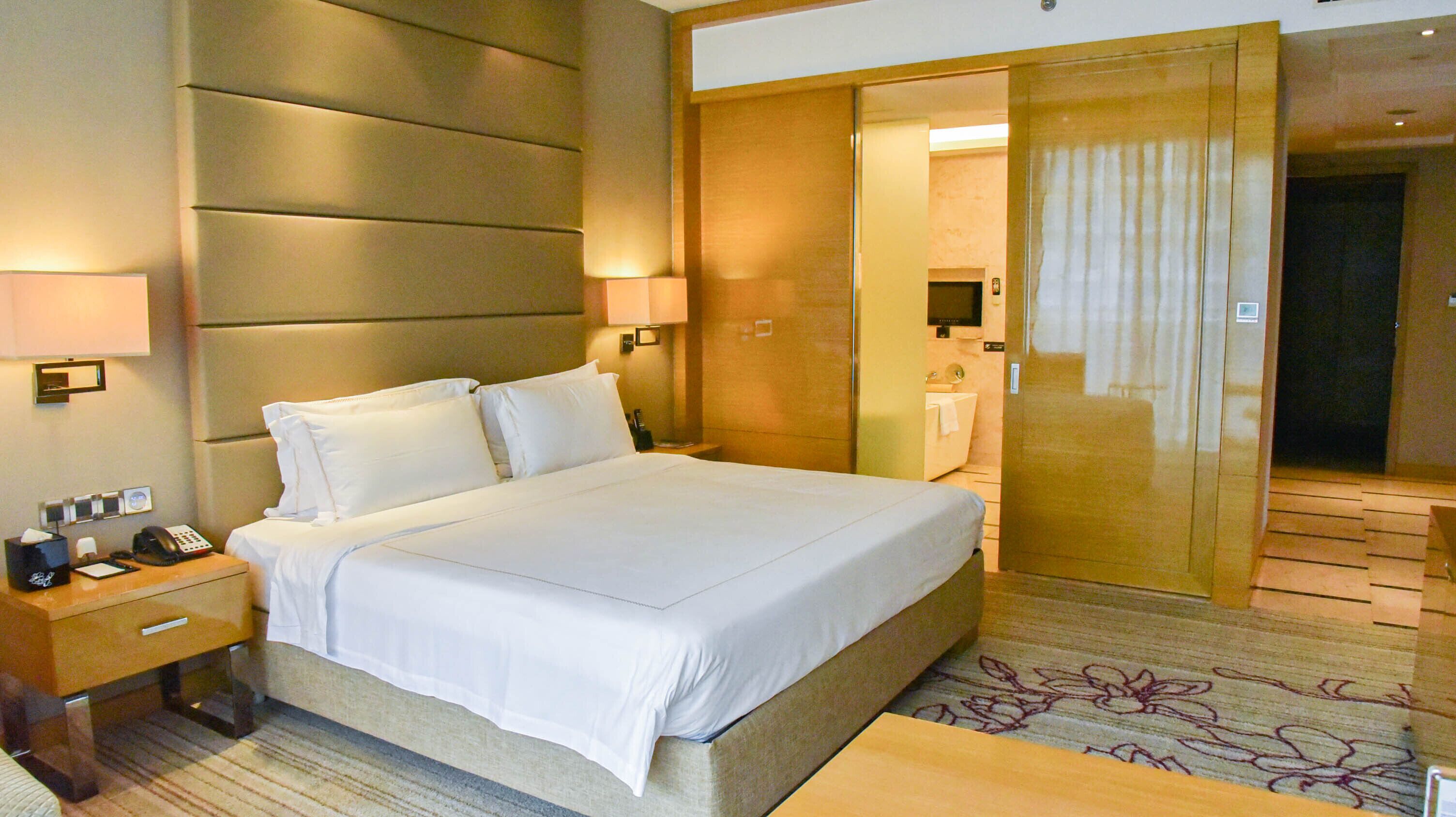 Ein Hotelzimmer mit einem großen Bett, Nachttischlampen, einem Telefon und einem Nachttisch.