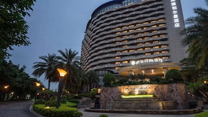 Un hotel con fachada curva, varios balcones y una entrada bien iluminada.