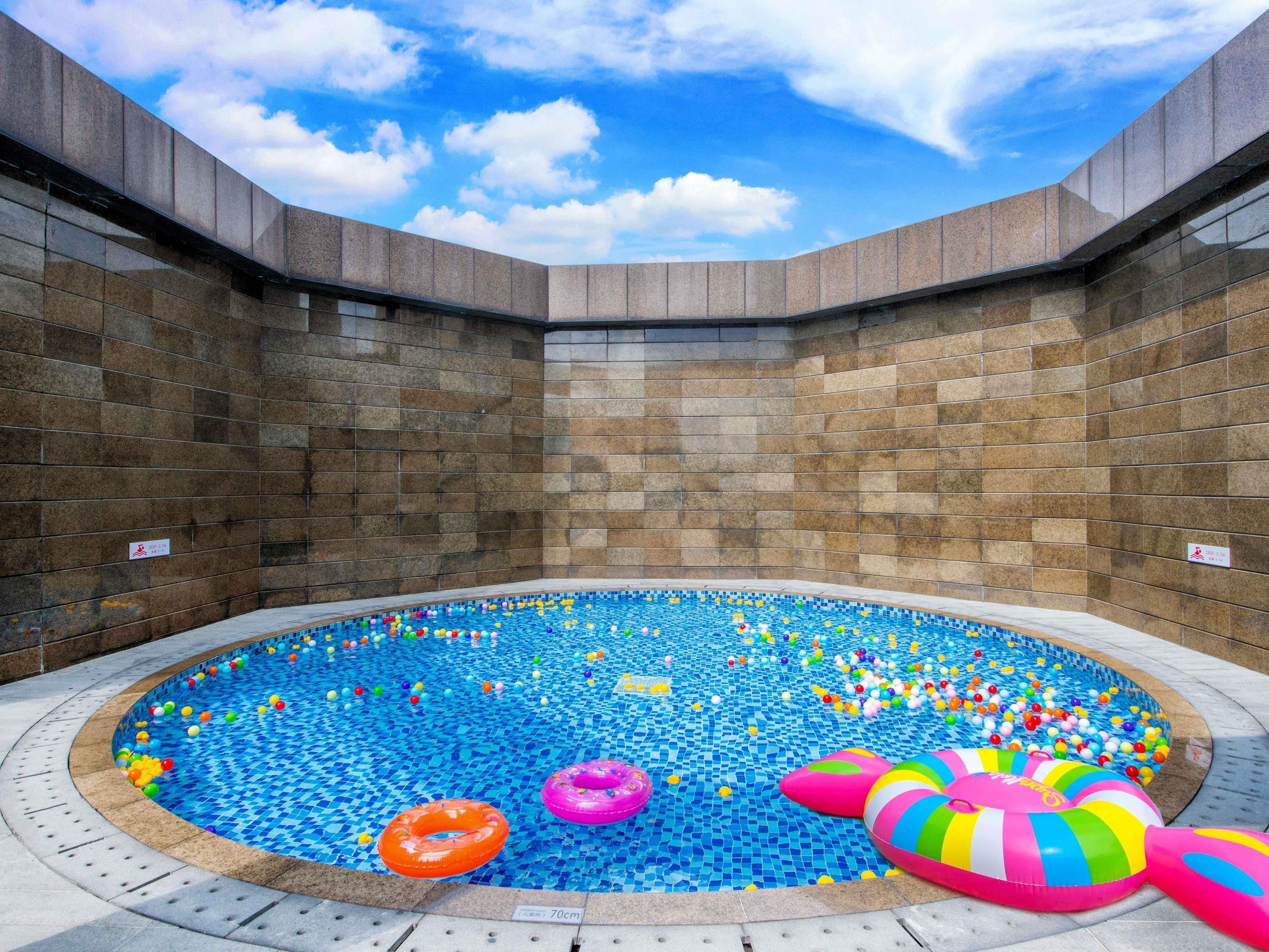 Una piscina con piso y paredes de azulejos, rodeada por una estructura de piedra.