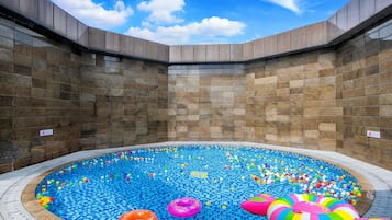 Una piscina con piso y paredes de azulejos, rodeada por una estructura de piedra.