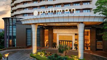 A hotel entrance with a curved facade, a prominent 'pullman' sign, and a landscaped garden area.