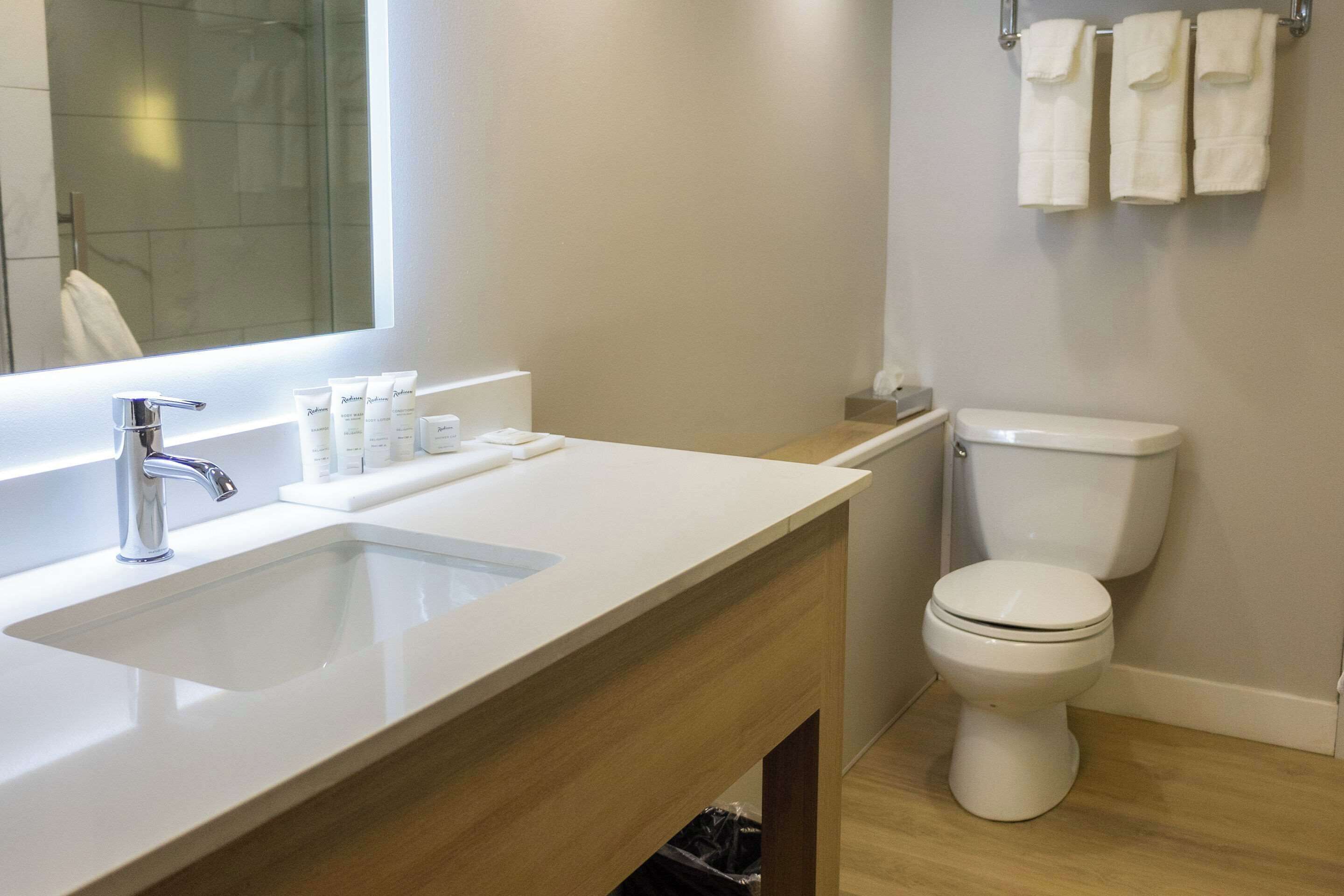 Casa de banho moderna com lavatório branco, espelho e sanita.
