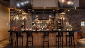Eine Bar mit einer Steinsäule, einer Holztheke und mehreren Barhocker.