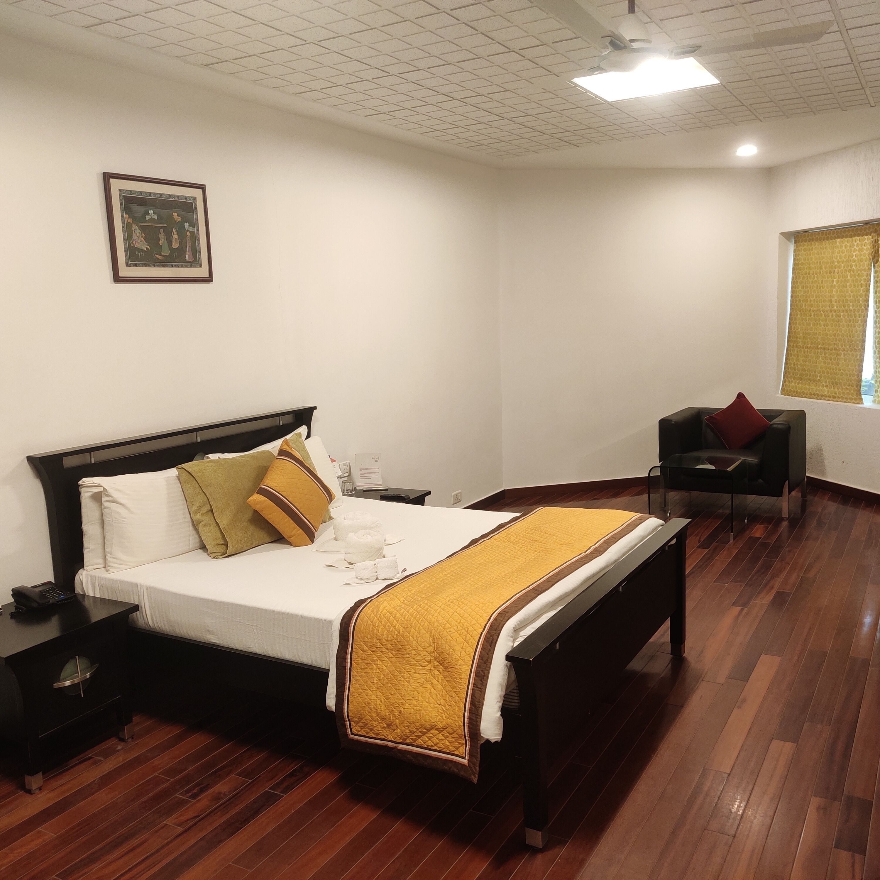 Een hotelkamer met een bed, nachtkastje en stoel.