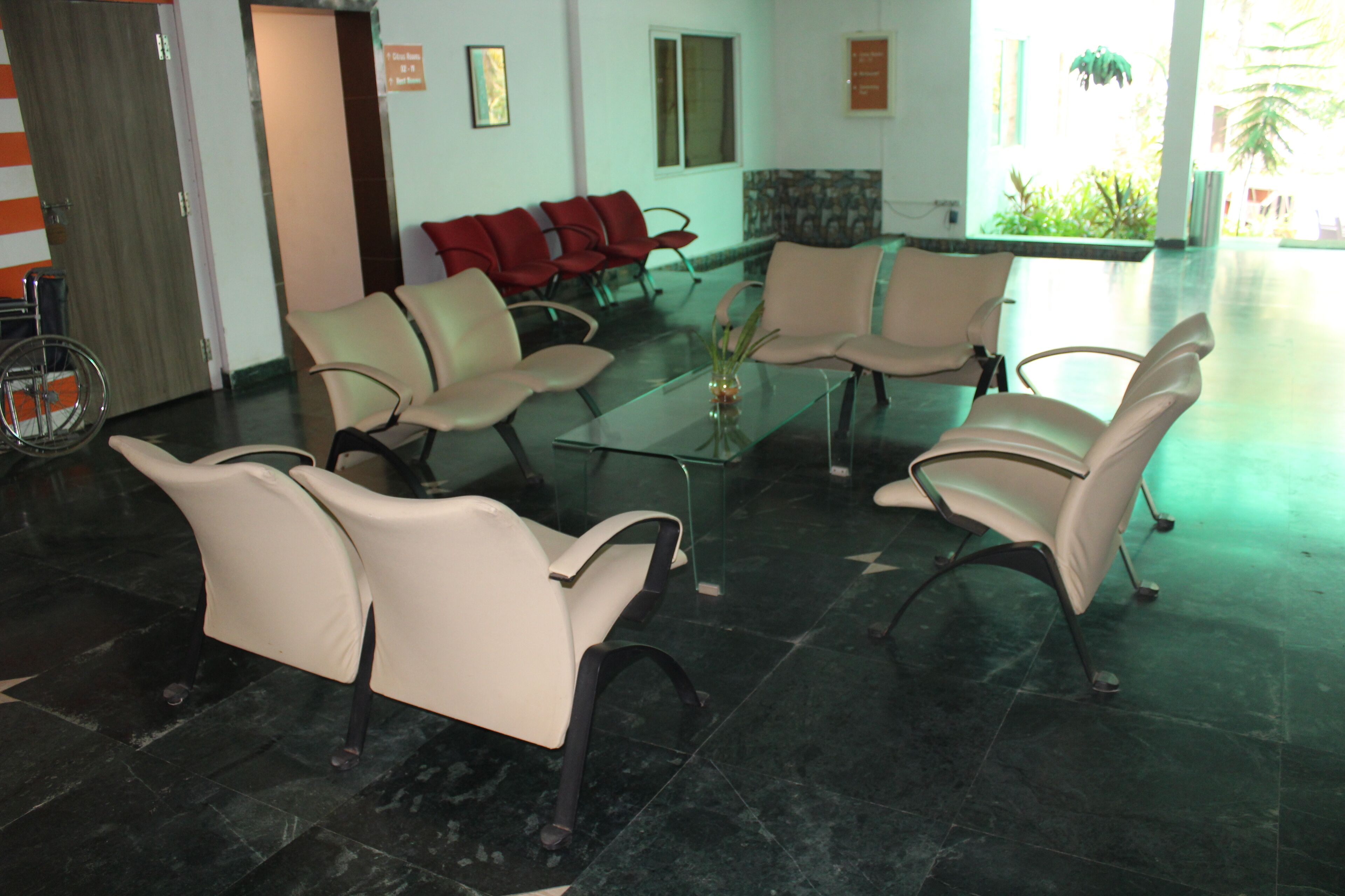 A waiting area with several chairs and a glass table, a reception desk, and a door.
