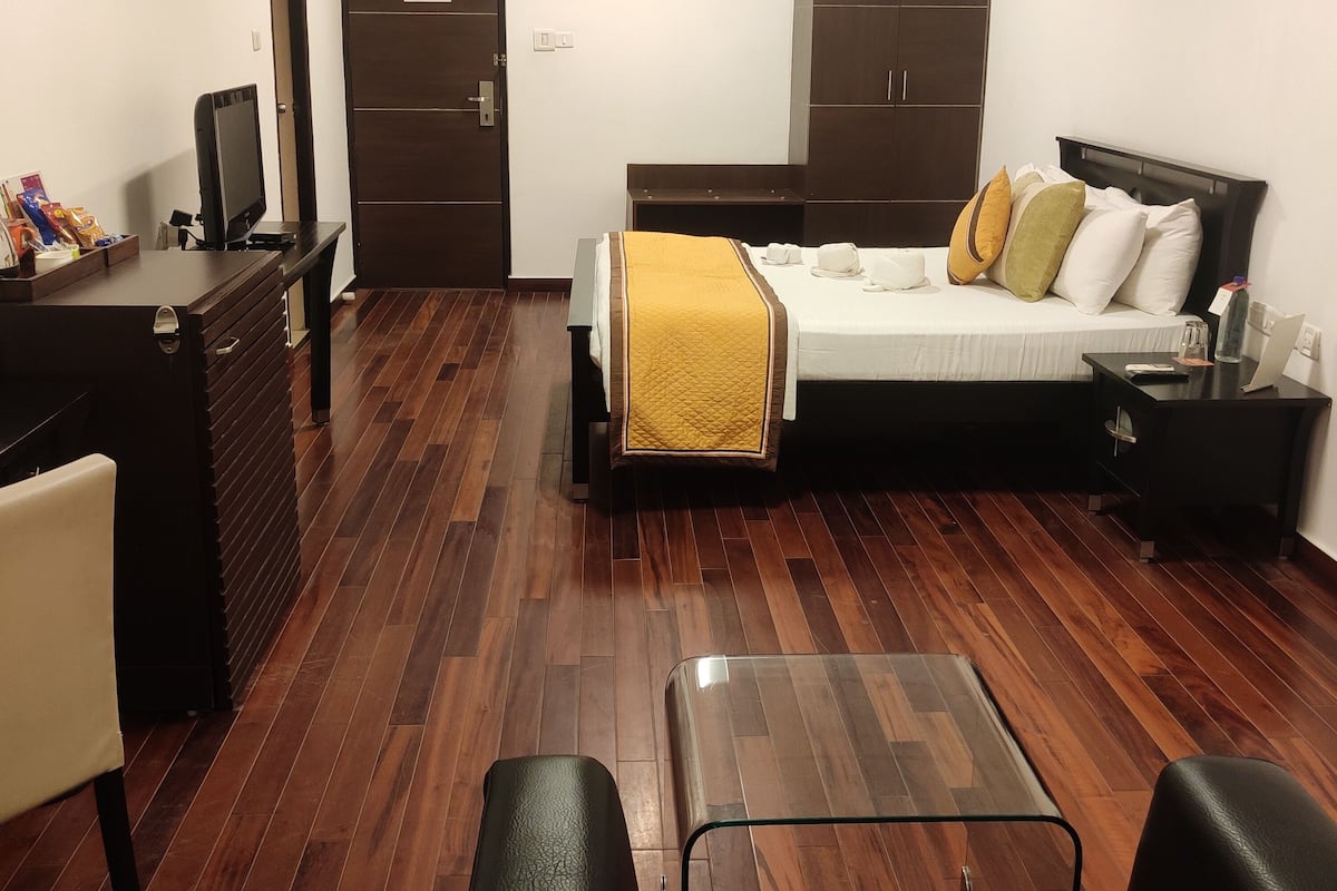 Een kleine hotelkamer met een bed, bureau, stoel, kledingkast en televisie.
