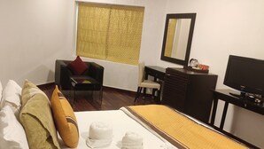 Une chambre d’hôtel équipée d’un lit, d’un bureau, d’une chaise, d’une télévision et d’une fenêtre avec des rideaux.
