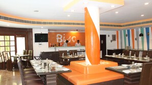 Un restaurant dont l’élément central est une décoration orange, avec plusieurs tables et chaises pour les clients.