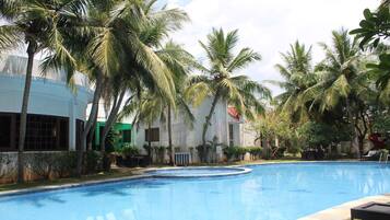 Una piscina rodeada de palmeras y un edificio con ventanas amplias.
