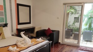 Une chambre d’hôtel équipée d’un lit, d’un bureau, d’une chaise et d’une porte-fenêtre coulissante donnant sur un espace extérieur.