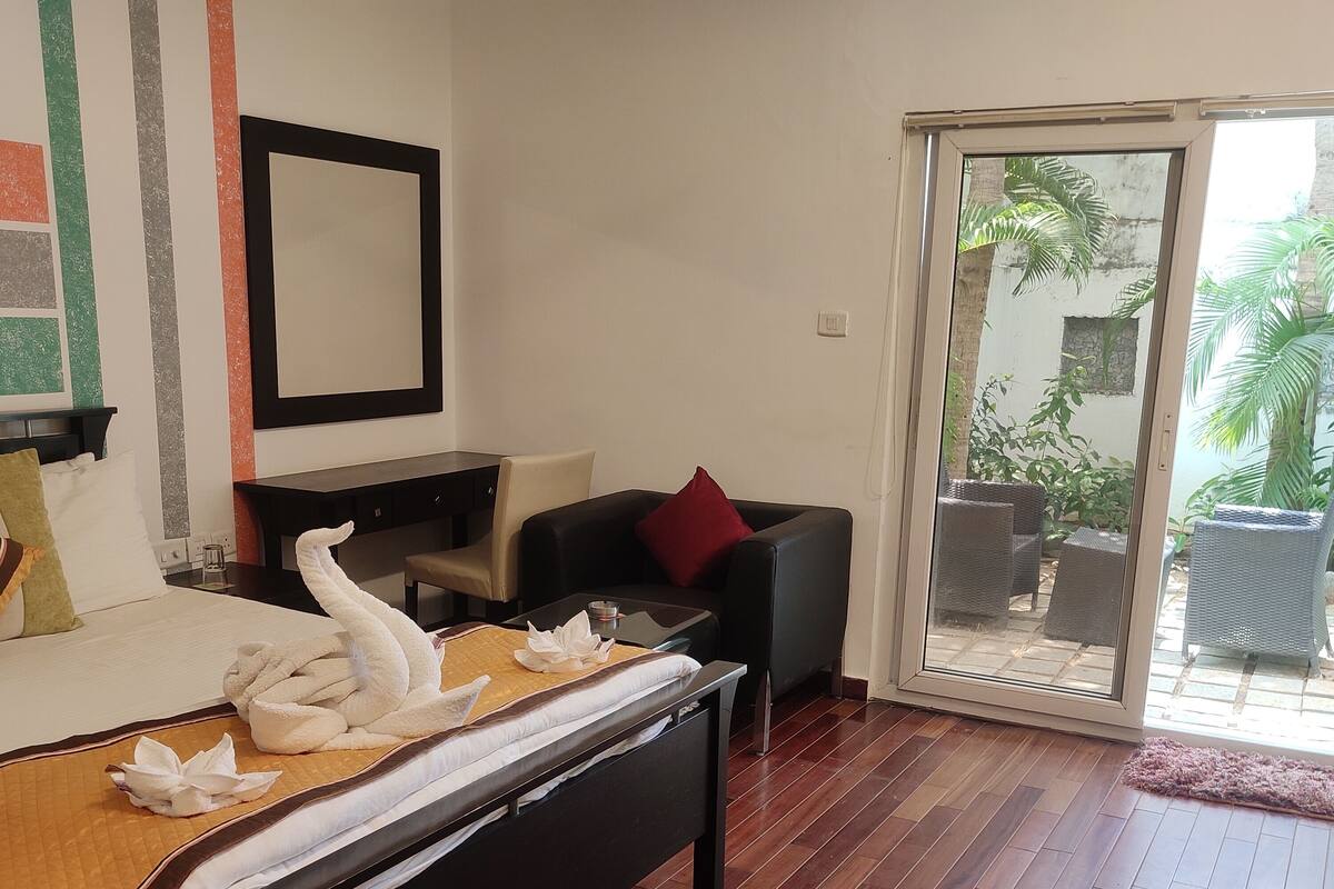 Een hotelkamer met een bed, een bureau, een stoel en een schuifdeur die uitkomt op een terras.