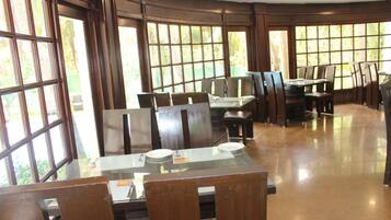 A restaurant with large windows, wooden furniture, and a polished floor.