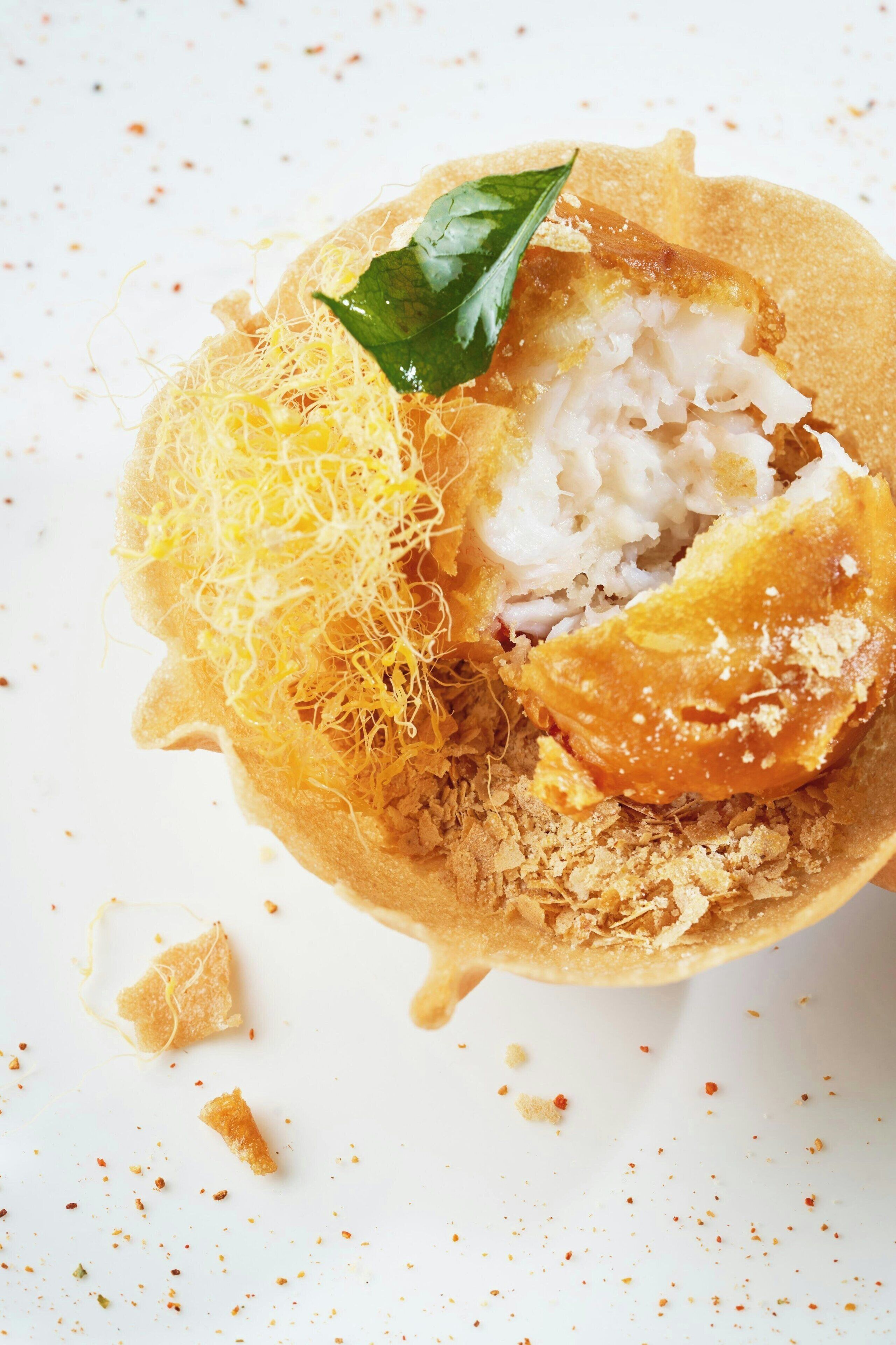 A dessert with shredded coconut, a leaf garnish, and a crispy base.