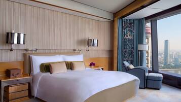 A modern hotel room with a large bed, a nightstand, a desk, and a view of the city.