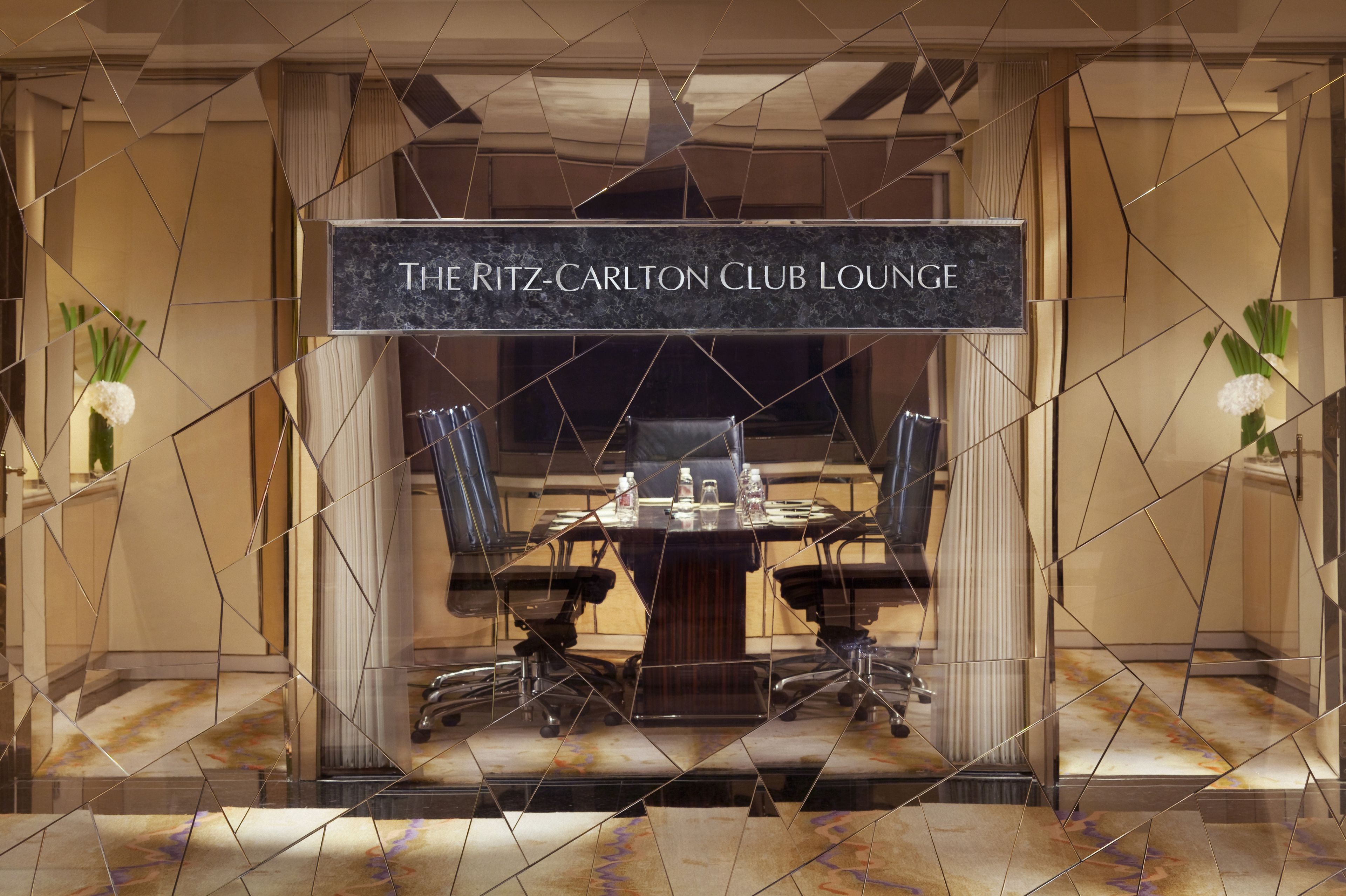 Un salón de conferencias con una mesa, sillas y un cartel que dice 'The Ritz-Carlton Club Lounge'.
