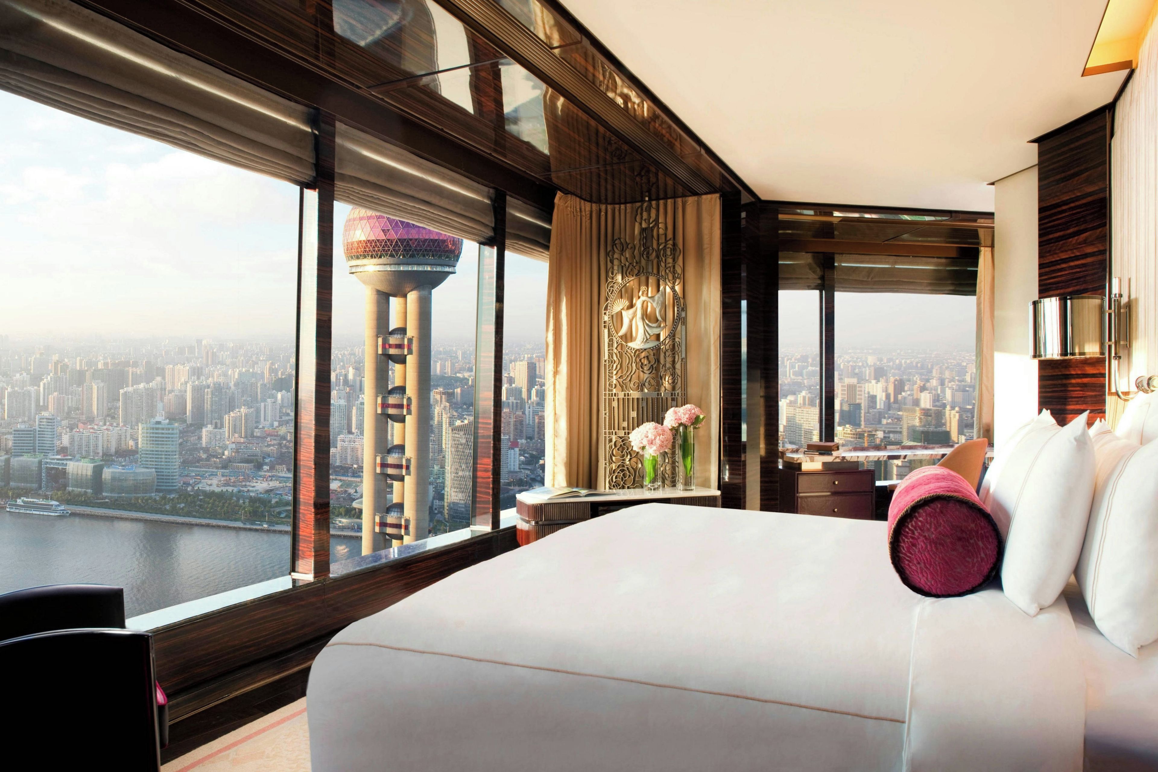 Habitación de hotel en un rascacielos con vista a la ciudad, cama grande y un panel decorativo en la pared.