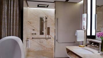 A modern bathroom with a bathtub, a walk-in shower, and a vanity with a mirror.