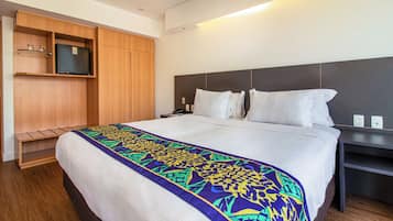 Une chambre d’hôtel avec un grand lit, une armoire en bois, une table de chevet et un téléviseur à écran plat.