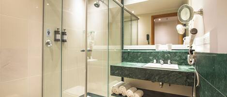 Un baño moderno con ducha envuelta en vidrio, un lavabo de mármol y un espejo grande.