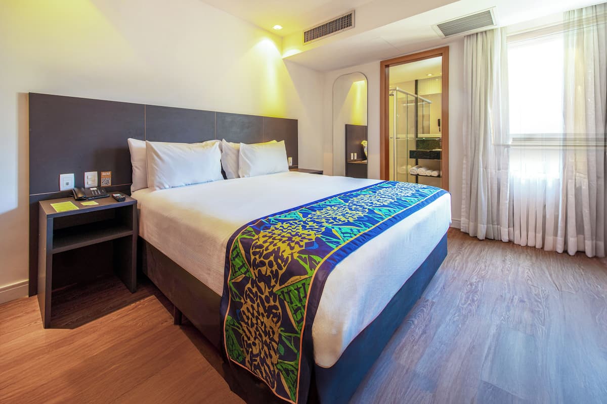 A hotel room with a bed, bedside table, and a bathroom visible through an open door.