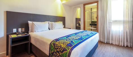 A hotel room with a bed, bedside table, and a bathroom visible through an open door.