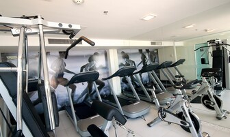 A gym with multiple treadmills, a rowing machine, and a wall with fitness posters.